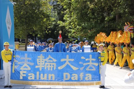European Tian Guo Marching Band mit dem Falun-Dafa-Banner und Drachentanz auf einem Platz in Athen, 2023