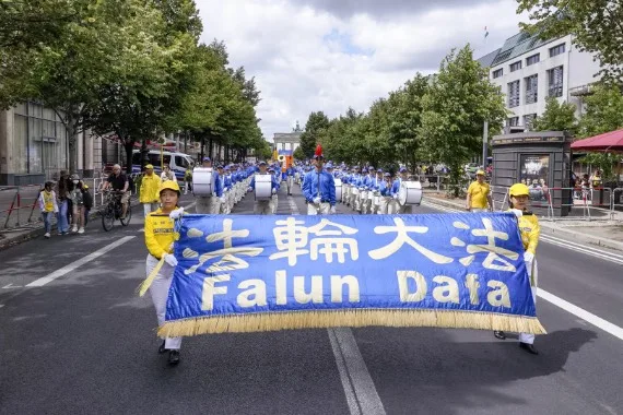 European Tian Guo Marching Band mit dem Falun-Dafa-Banner auf der Straße des 17. Juni, im Hintergrund das Brandenburger Tor, Berlin 2022