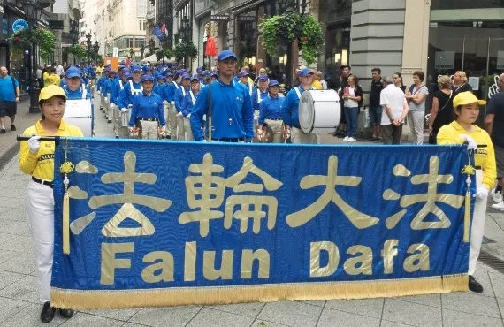 European Tian Guo Marching Band mit dem Falun-Dafa-Banner in einer Fußgängerzone in Budapest, 2022