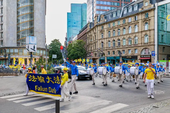 European Tian Guo Marching Band überquert mit ihren Trommlern eine Kreuzung im Frankfurter Bankenviertel, 2026