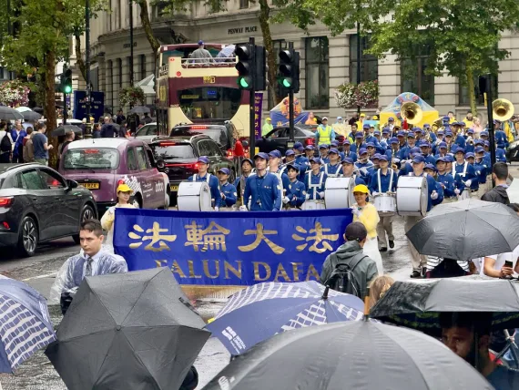 Zuschauer mit Regenschirmen verfolgen die Parade der European Tian Guo Marching Band in London, 2025