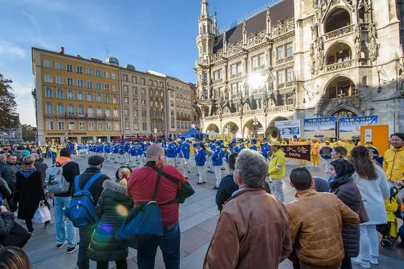 Zuschauer verfolgen den Auftritt der European Tian Guo Marching Band auf dem Marienplatz vor dem Neuen Rathaus in München, 2021