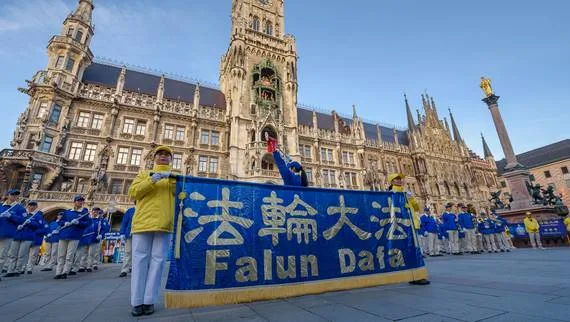 European Tian Guo Marching Band mit dem Falun-Dafa-Banner vor dem Neuen Rathaus und der Mariensäule auf dem Münchner Marienplatz, 2021