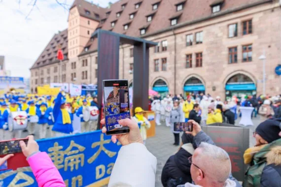 Zuschauer filmen die Kundgebung der European Tian Guo Marching Band mit ihren Smartphones, Nürnberg 2023
