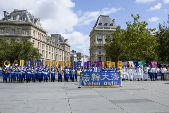 European Tian Guo Marching Band in Aufstellung mit farbigen Fahnen auf einem Platz in Paris, 2023