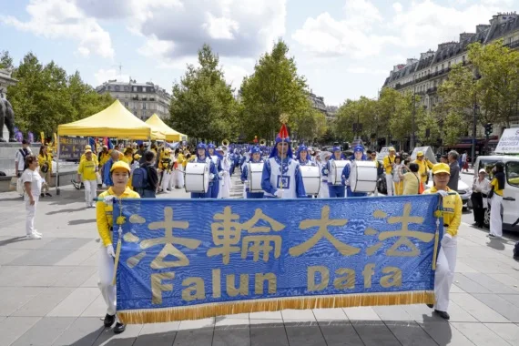 European Tian Guo Marching Band mit dem Falun-Dafa-Banner auf einem Platz in Paris, 2023