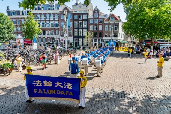 European Tian Guo Marching Band auf einem Platz mit Grachtenhäusern in Amsterdam, 2025