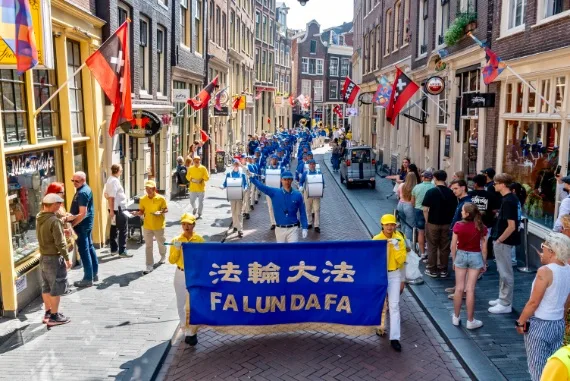 European Tian Guo Marching Band in einer engen Gasse mit Amsterdamer Stadtflaggen, 2025