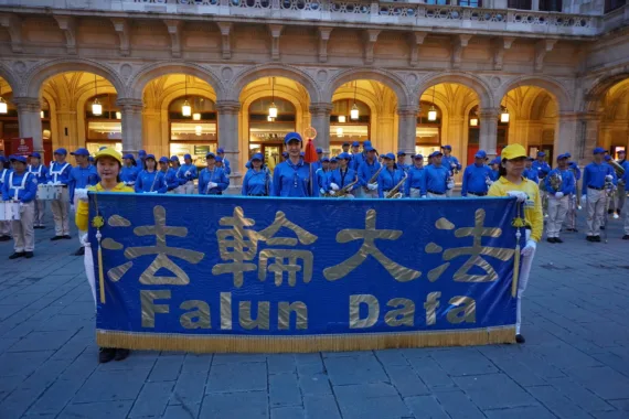 European Tian Guo Marching Band mit dem Falun-Dafa-Banner vor einem beleuchteten Arkadengang in Wien, 2023