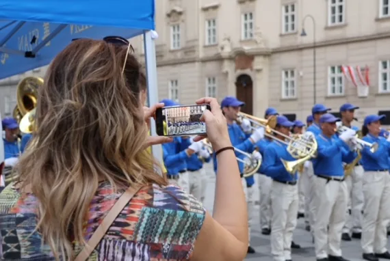 Eine Person im Publikum fotografiert das Blechbläserregister der European Tian Guo Marching Band mit dem Smartphone, Wien 2024