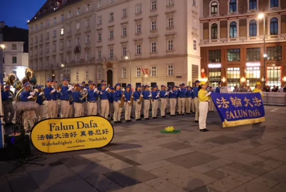 Abendliche Kundgebung der European Tian Guo Marching Band mit Falun-Dafa-Schildern in Wien, 2024
