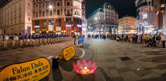 Abendliche Kundgebung der European Tian Guo Marching Band mit beleuchteter Lotusblume in der Wiener Innenstadt, 2025