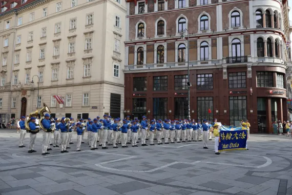 European Tian Guo Marching Band in Aufstellung mit Falun-Dafa-Transparent vor dem Start der Parade in der Wiener Innenstadt, 2026