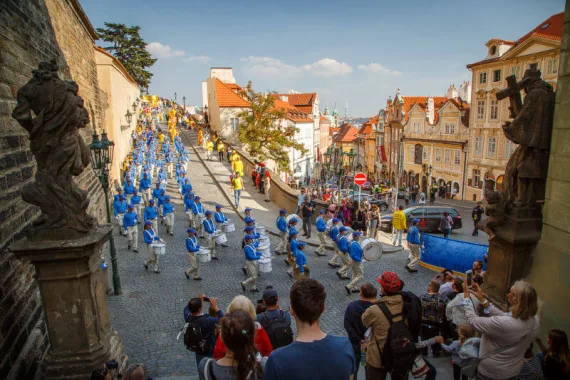 European Tian Guo Marching Band marschiert die alte Schlosstreppe zur Prager Kleinseite hinab, gesäumt von Barockstatuen und Zuschauern