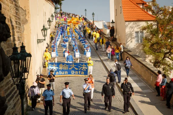 European Tian Guo Marching Band zieht mit Falun-Dafa-Banner und Drachentanz die Prager Schlosstreppe hinunter, begleitet von der Polizei
