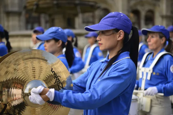 Nahaufnahme beim Beckenspiel der European Tian Guo Marching Band, dahinter weitere Musikerinnen und Musiker mit Trommeln
