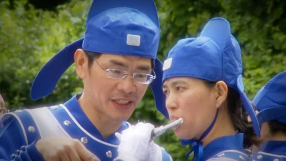 Nahaufnahme zweier Mitglieder der European Tian Guo Marching Band in traditioneller blauer Uniform beim Flötenspiel